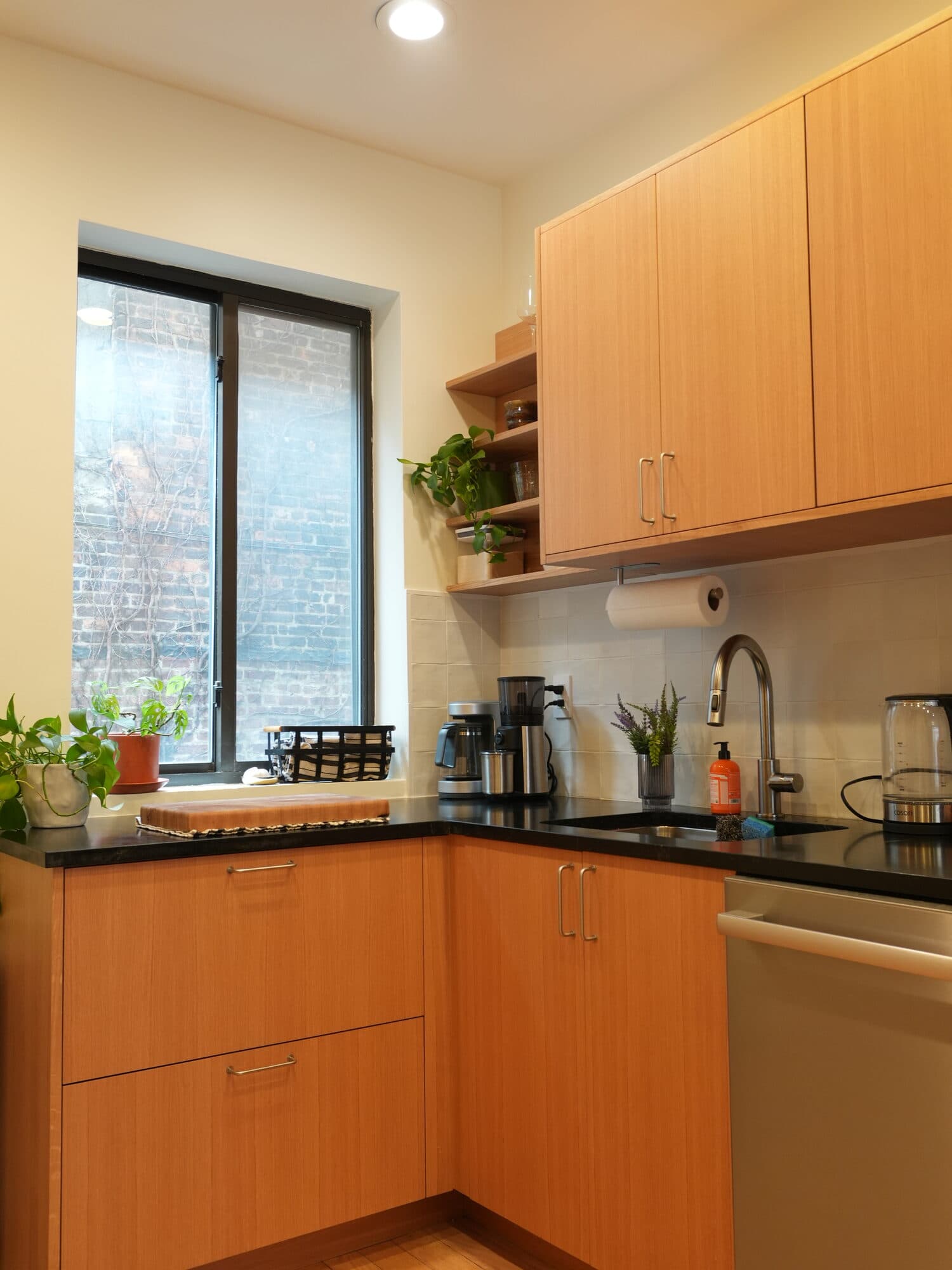 Greenpoint kitchen with window over the counter, open dish storage, and oak lower cabinets