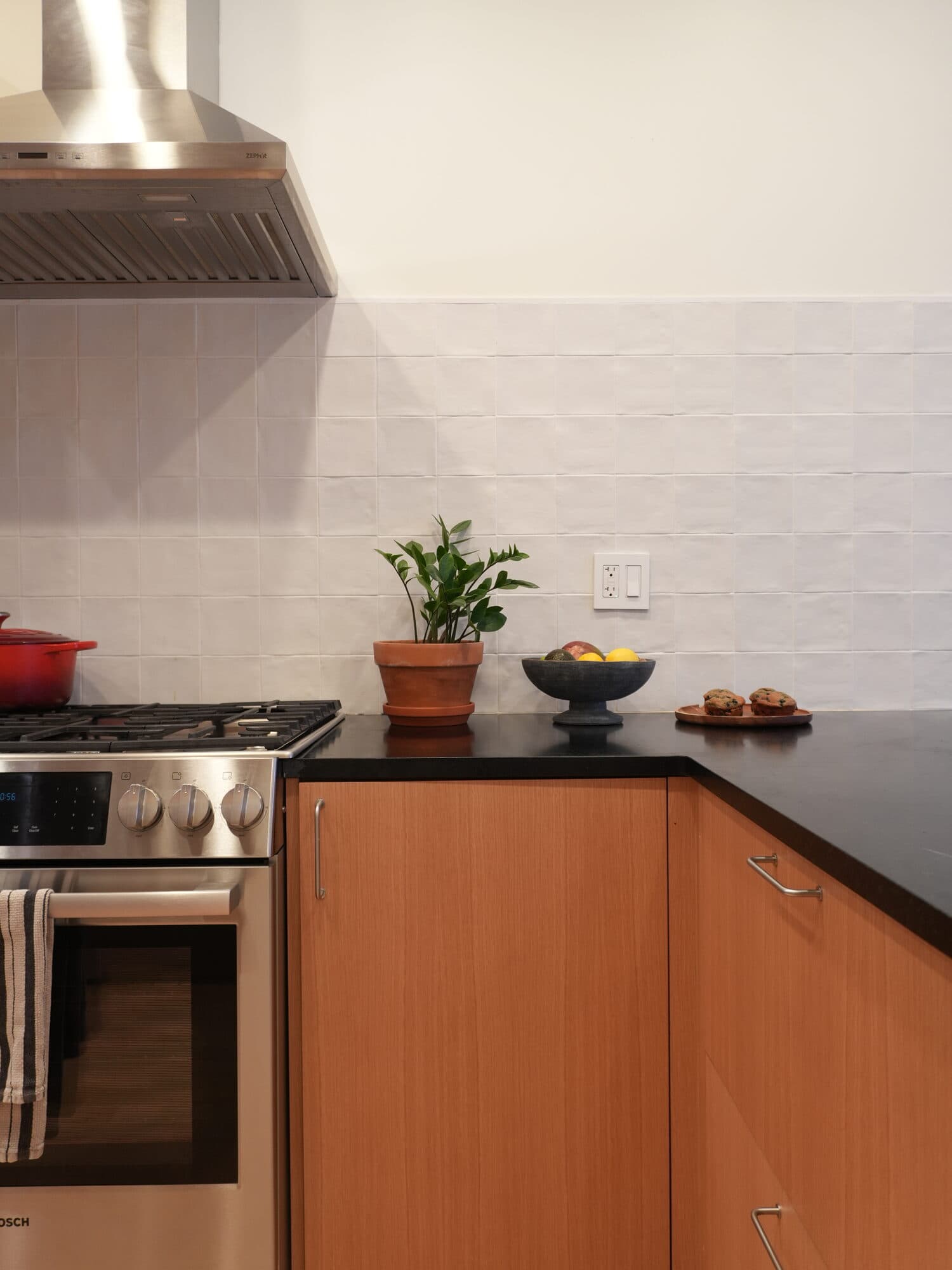 Stainless range and hood set into oak cabinetry with a white tile backsplash