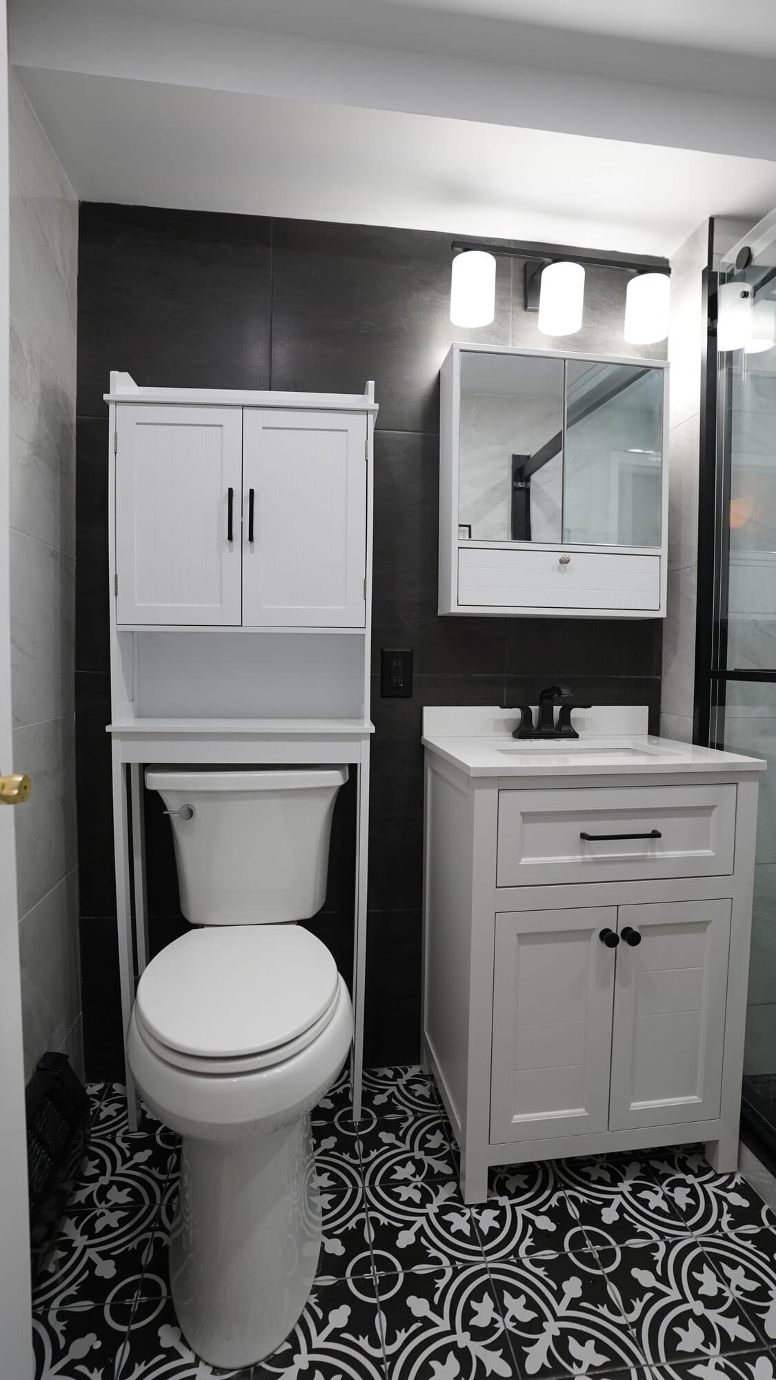 Black-and-white patterned floor tile with white storage cabinetry in the renovated bathroom
