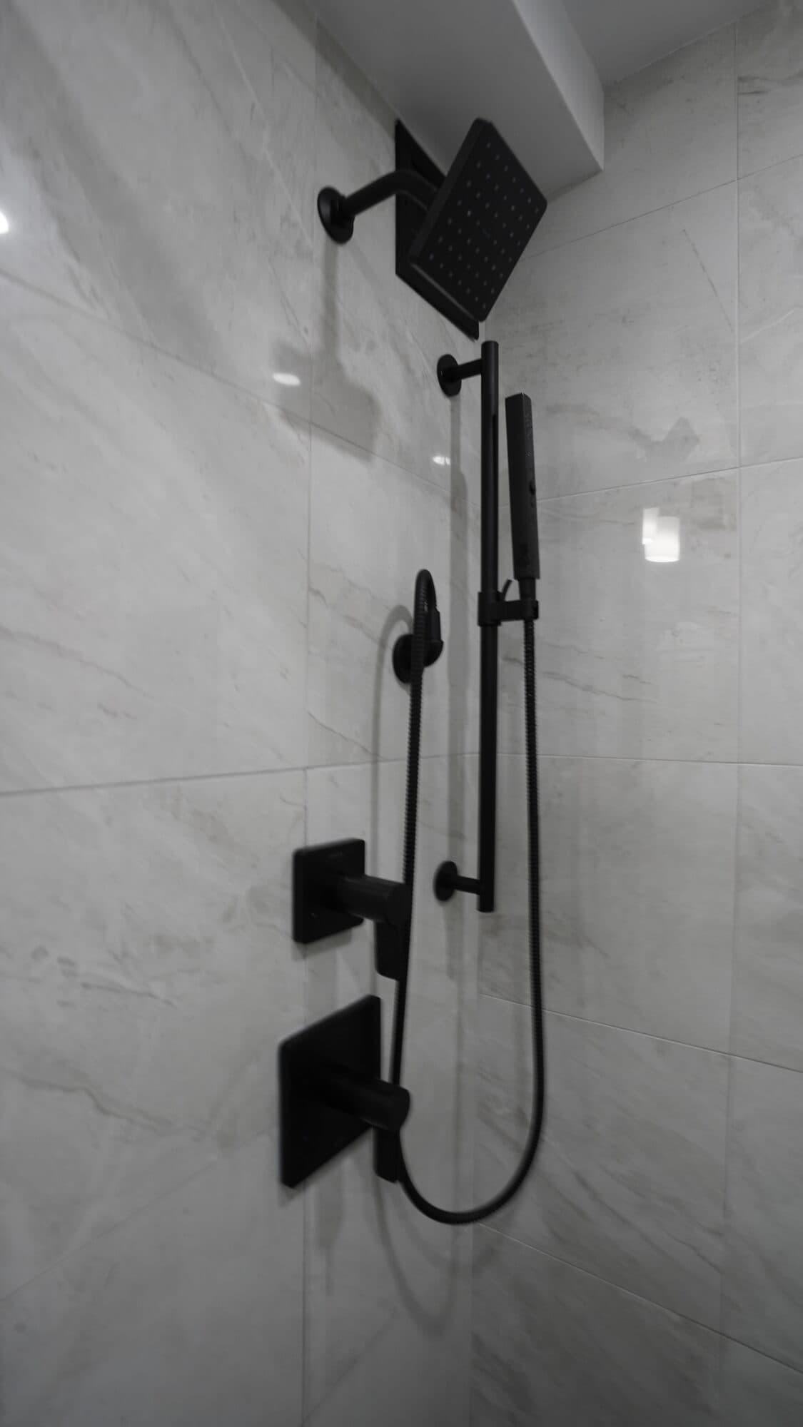 Matte black shower set with slide bar and square rain head on marble-look tile