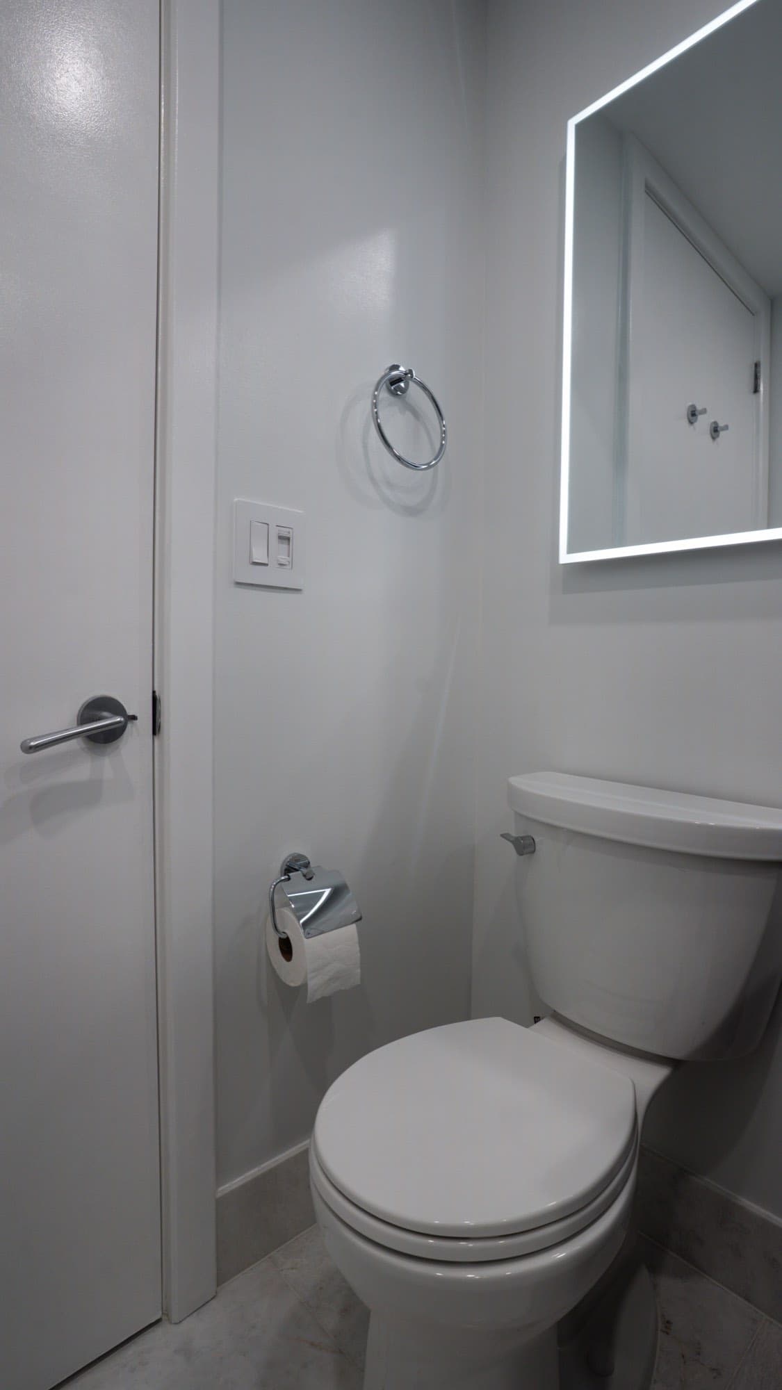 Chrome accessories and backlit mirror in the renovated Brooklyn condo bathroom
