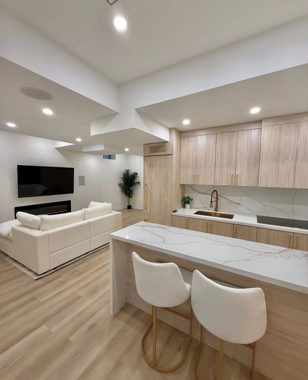 Kitchenette and den of the renovated FiDi apartment with island seating and wall-mounted TV