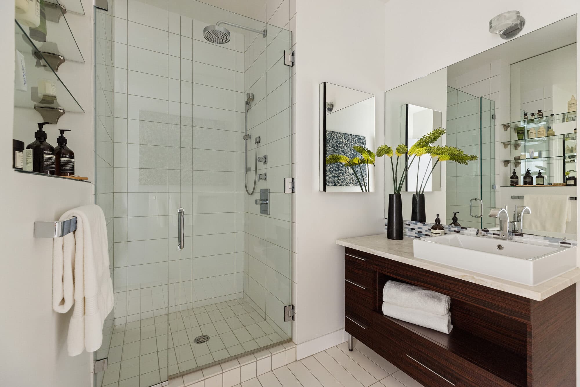 Glass-enclosed walk-in shower with white tile in the renovated bathroom