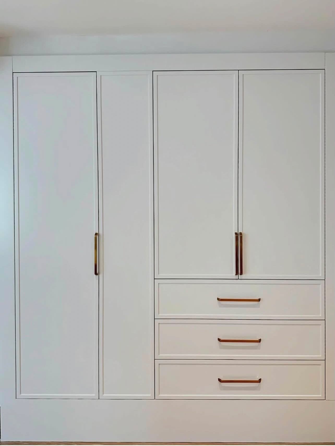 Floor-to-ceiling pantry wall with inset shaker doors and brass pulls