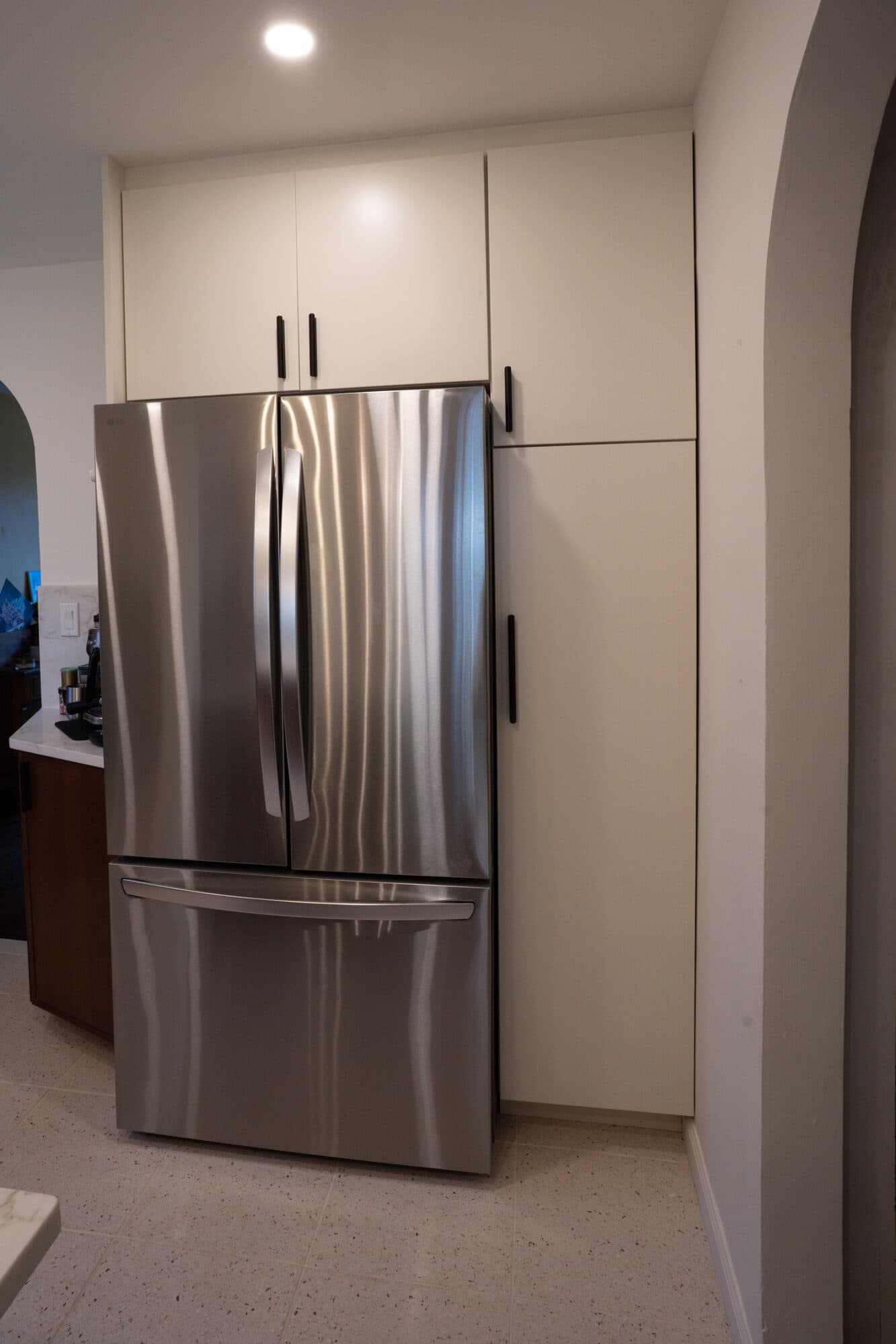 Stainless refrigerator built into white cabinetry in the renovated kitchen