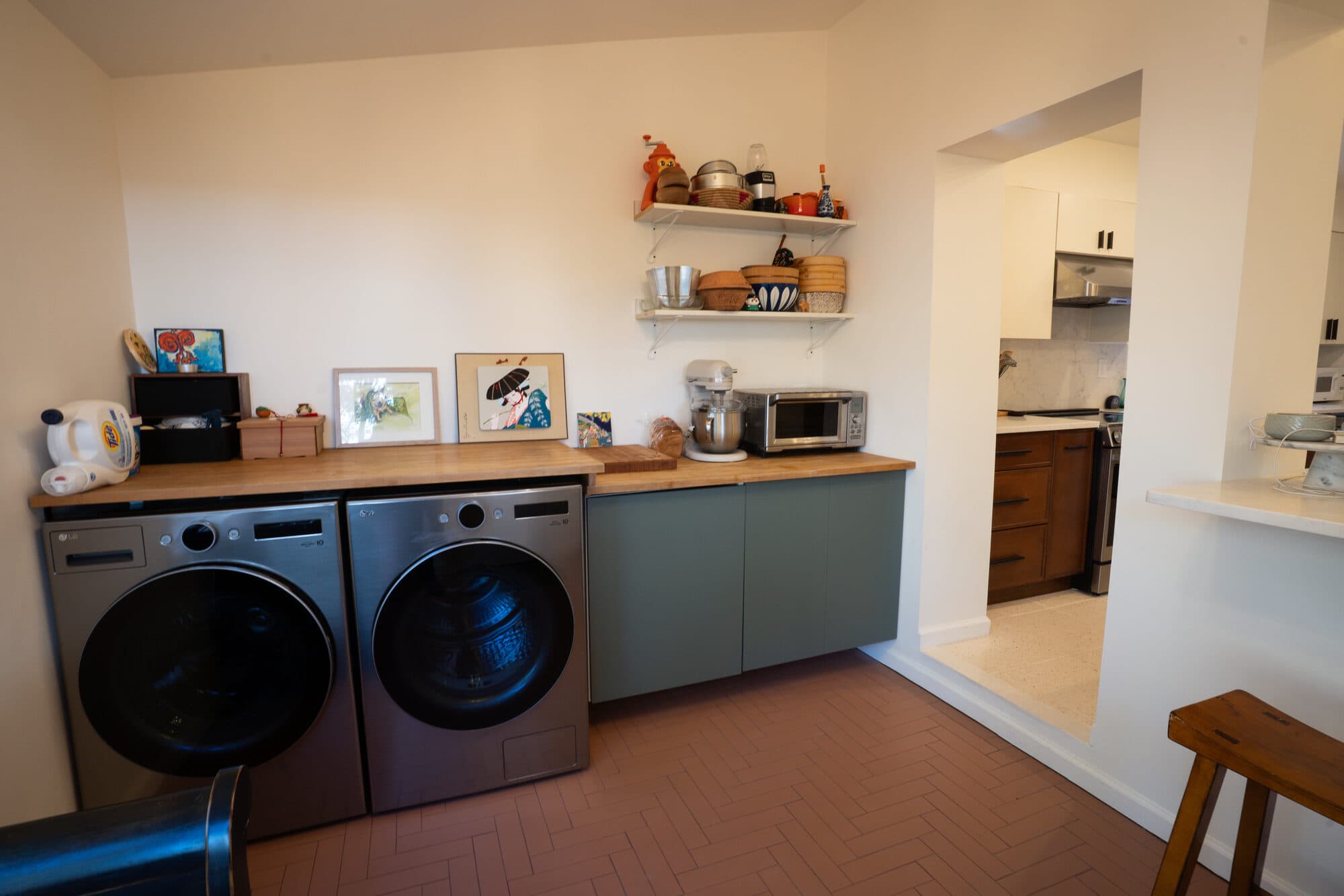 Laundry nook with green cabinetry beside the kitchen pass-through